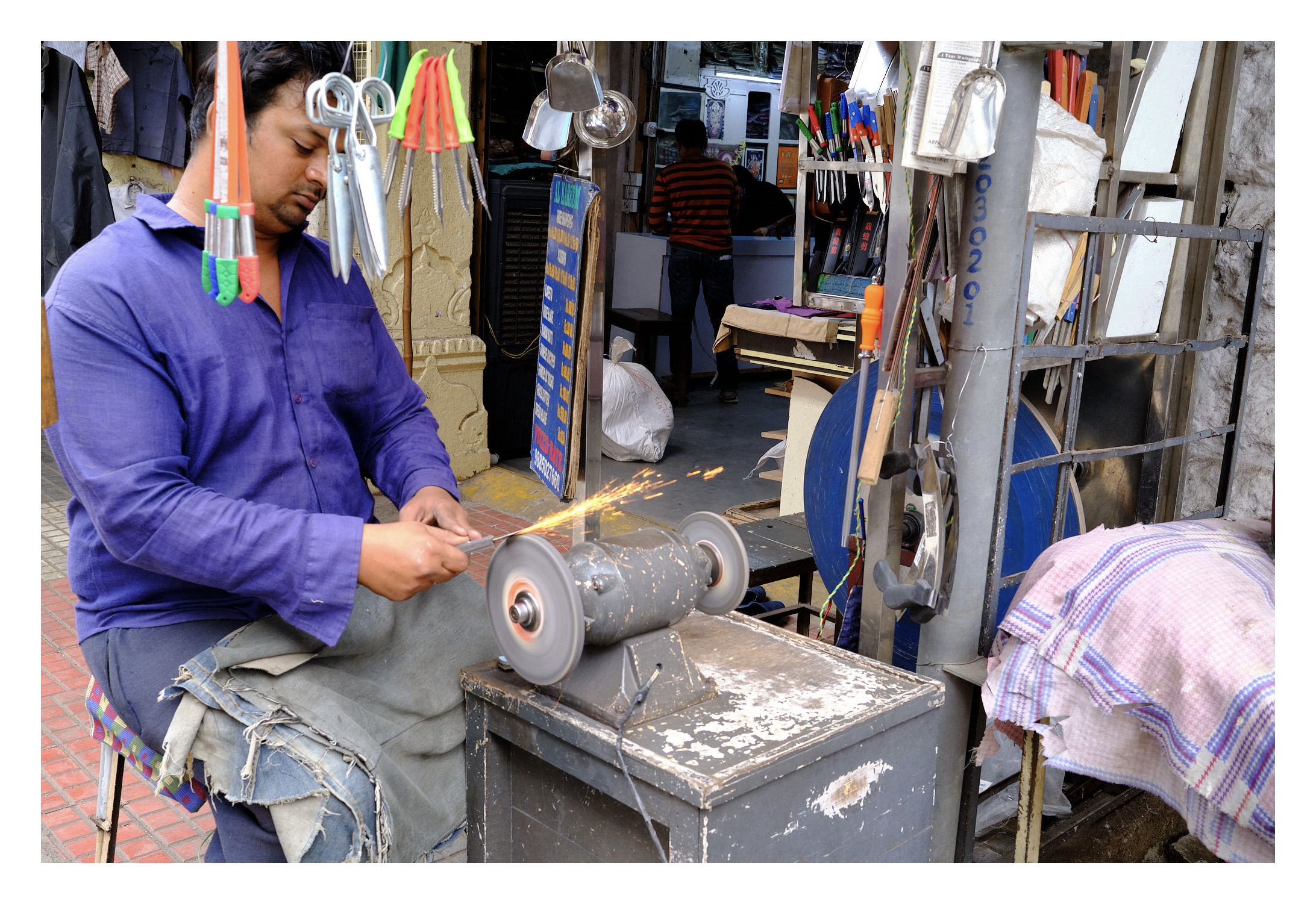 man sharpening the knife of circular whetstone. Sparks can be seen from the knife