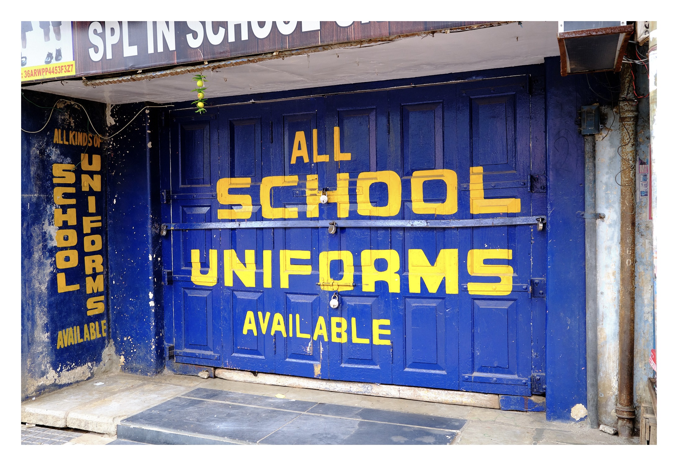 a vibrant blue store front with 'all school uniforms available here' written on the wooden door