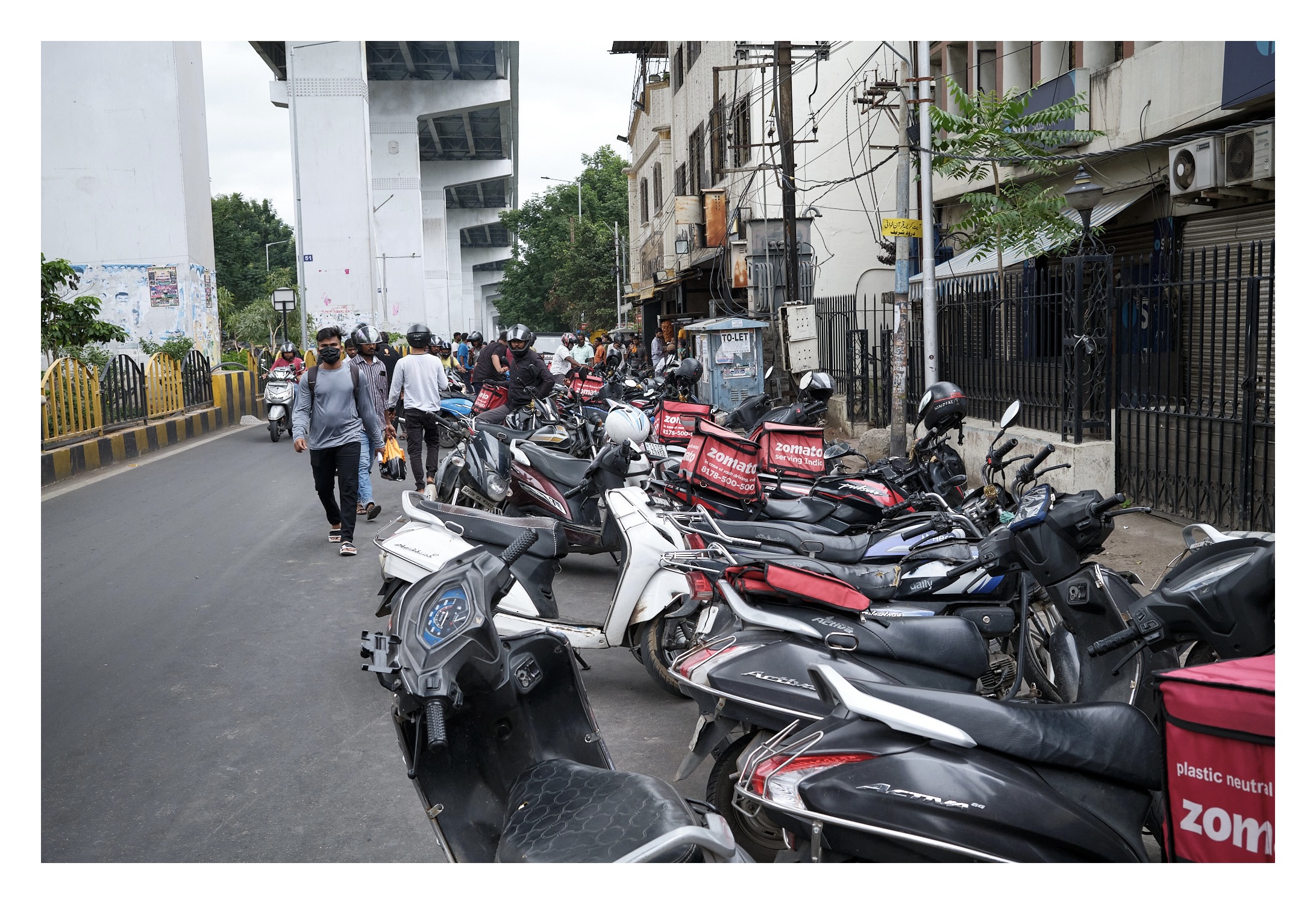 a group of zomato delivery riders waiting with their bikes opposite to bwarchi restaurant